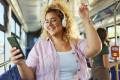 Happy overweight woman listening music over cell phone in a bus.